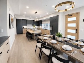 A modern kitchen with dark cabinets, a central island, and a dining area set for a meal.