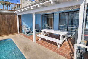 A poolside area with a white picnic table, chairs, and a pergola. - Private Townhome w/ private pool 1 block to beach 3 Bedroom Home by RedAwning (South Padre Island)