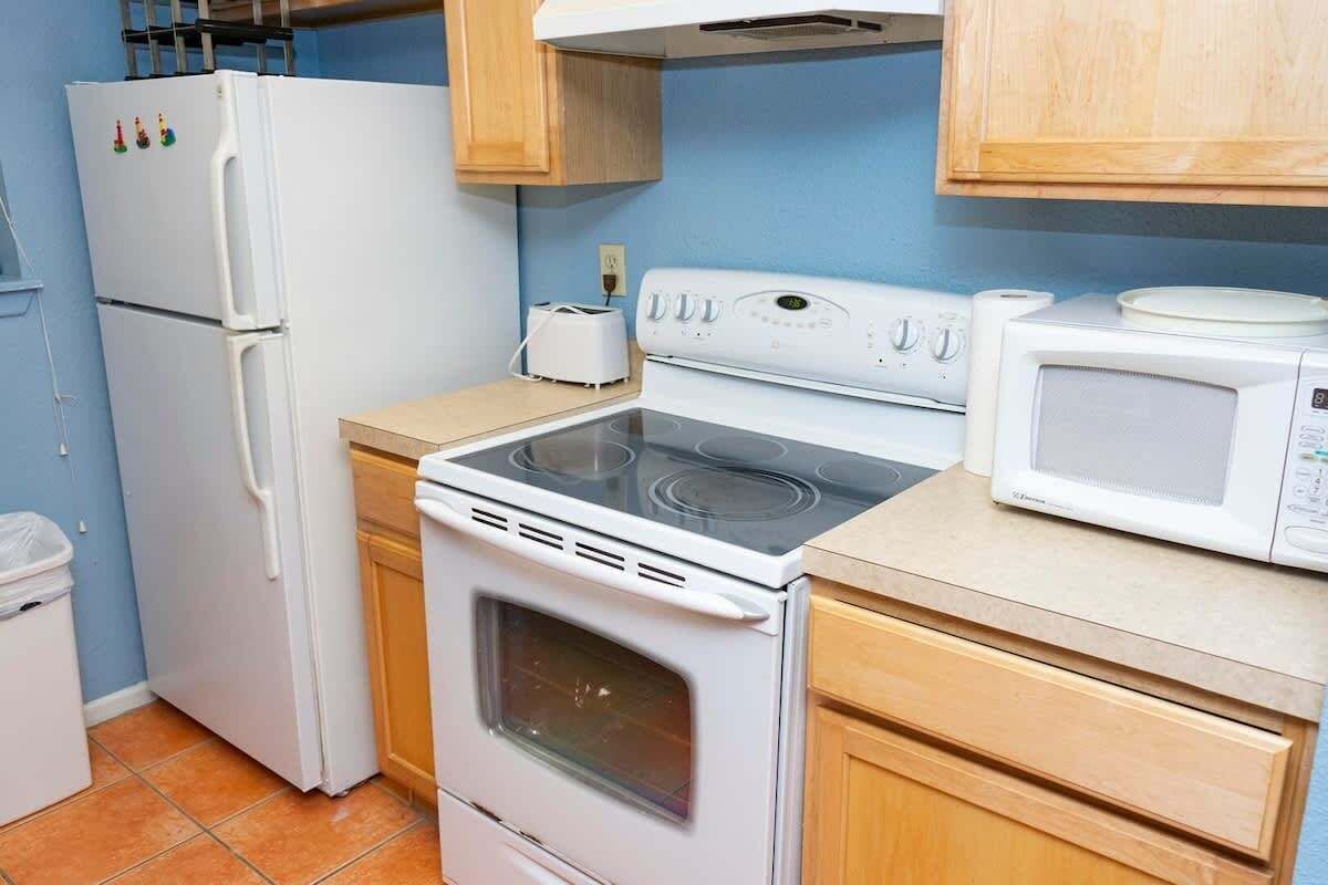 A compact kitchen with a white refrigerator, stove, and microwave.