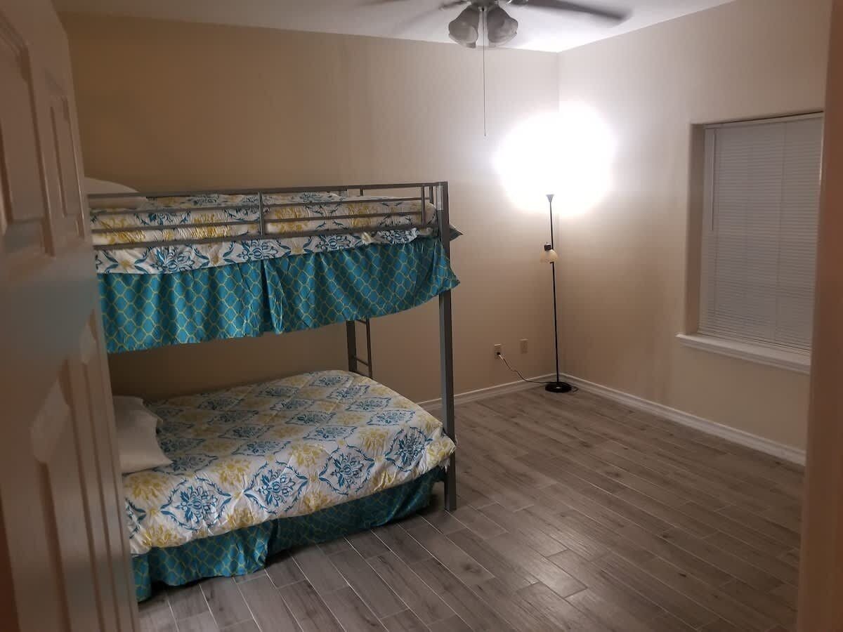Ein Zimmer mit Etagenbett, Stehlampe und Deckenventilator.