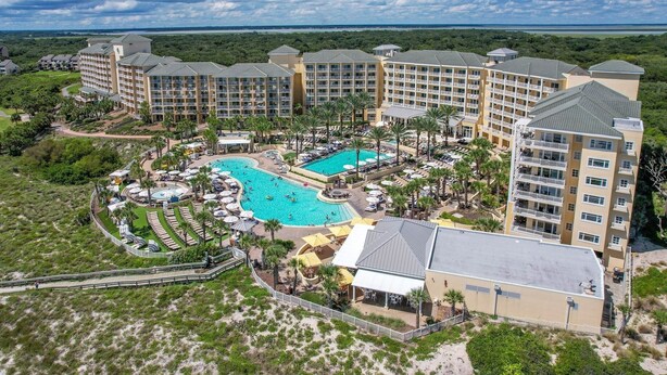 A resort with multiple buildings, a central pool, and surrounding greenery.