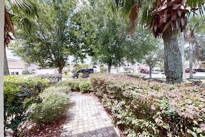 Stroll through the beautifully landscaped grounds, lined with a variety of shrubs and trees along a paved pathway.