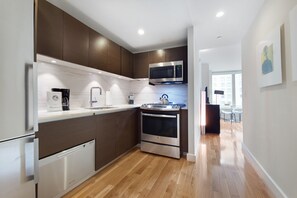A modern kitchen with stainless steel appliances, wooden cabinets, and a marble backsplash.