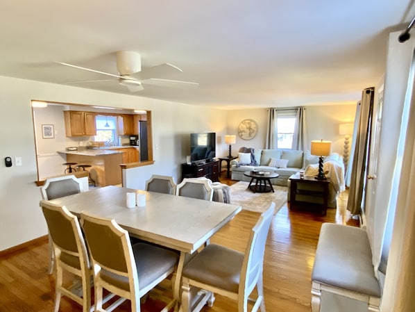 A spacious living area with a dining table, chairs, a sofa, and a TV.