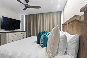 A bedroom with a bed, a ceiling fan, a TV, and a window with curtains. - ★New: Luxurious 4BD Oceanfront Condominium (Noord)