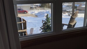 A window with a view of a snowy outdoor area, including a red car and a small Christmas tree. - Little Bluff Inn (Trempealeau)