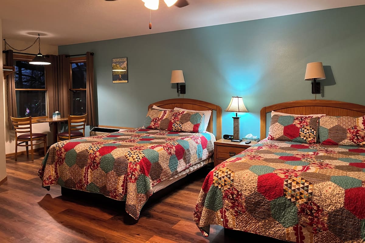 Habitación de hotel con dos camas, un escritorio y una silla.