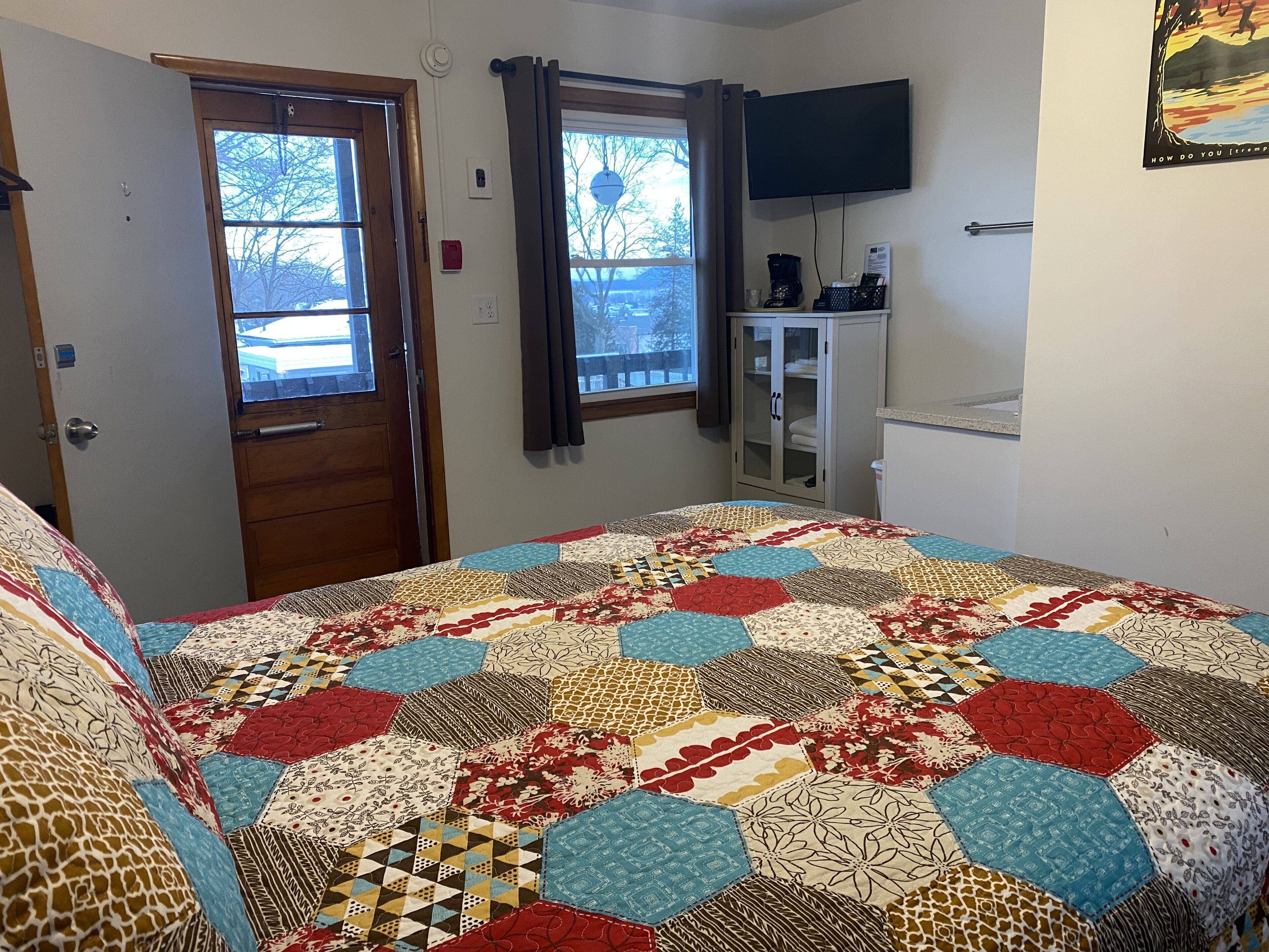 Un dormitorio con una cama grande, dos ventanas, una televisión y un armario.