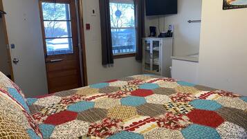 Un dormitorio con una cama grande, dos ventanas, una televisión y un armario.