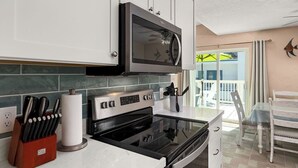 A kitchen with a microwave, stove, and knife block.
