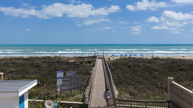 A boardwalk leading to a beach with a clear view of the ocean.