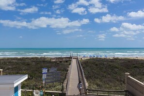 A boardwalk leading to a beach with a clear view of the ocean.