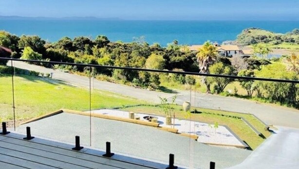 Un balcon offrant une vue sur un paysage côtier, comprenant une route et de la végétation.