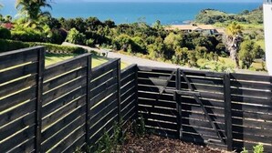 Un balcon avec vue sur l’océan et un paysage vallonné.