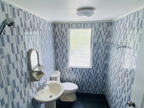 Bathroom features a checkered tile pattern, white sink, toilet, and window.