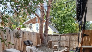 Un patio trasero con mesa y sillas techadas, una planta en maceta y una valla de madera.