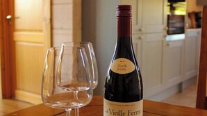 A bottle of wine and two empty wine glasses on a wooden table in a kitchen. - Cuddfan Lodge on a Beautiful Lake (Newport)