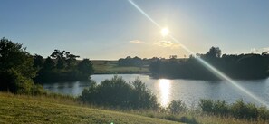 Une vue paisible sur un lac, avec un ciel dégagé et la lumière du soleil se reflétant sur l’eau.
