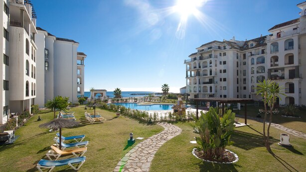 A resort with a swimming pool, lounge chairs, and a view of the ocean. - Lovely 2-Bed Apartment in Marina de la Duquesa (Puerto de la Duquesa)