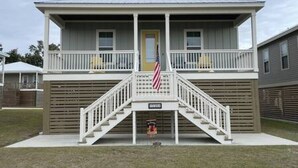 Ein zweistöckiges Haus mit Veranda und einer Treppe, die zum Eingang führt, sowie eine amerikanische Flagge.