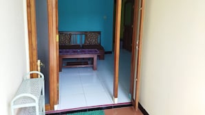 A room with a wooden door, a bench, and a small table. - Homestay Punokawan Borobudur (Borobudur)