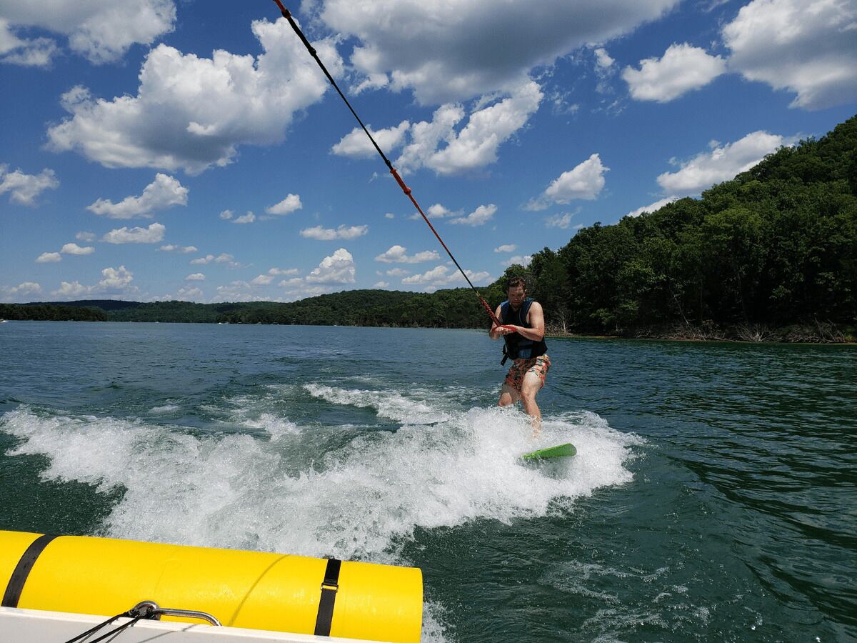 A person wakeboarding on a lake with a boat in the foreground.