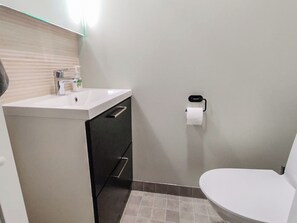 Une salle de bain avec un lavabo blanc, des toilettes et un porte-serviettes.