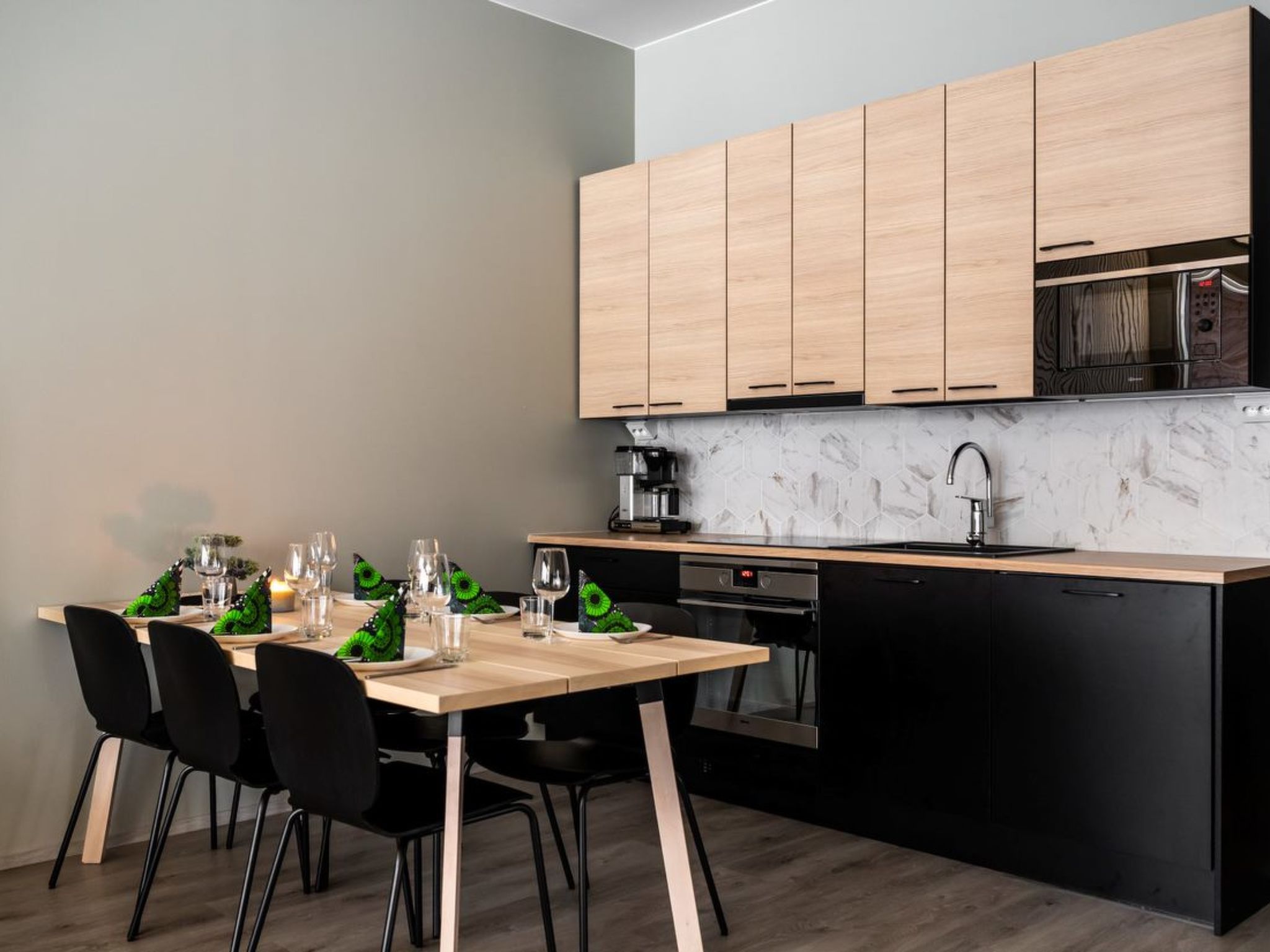A modern kitchen with wooden cabinets, a black countertop, and a dining area with a table set for four.