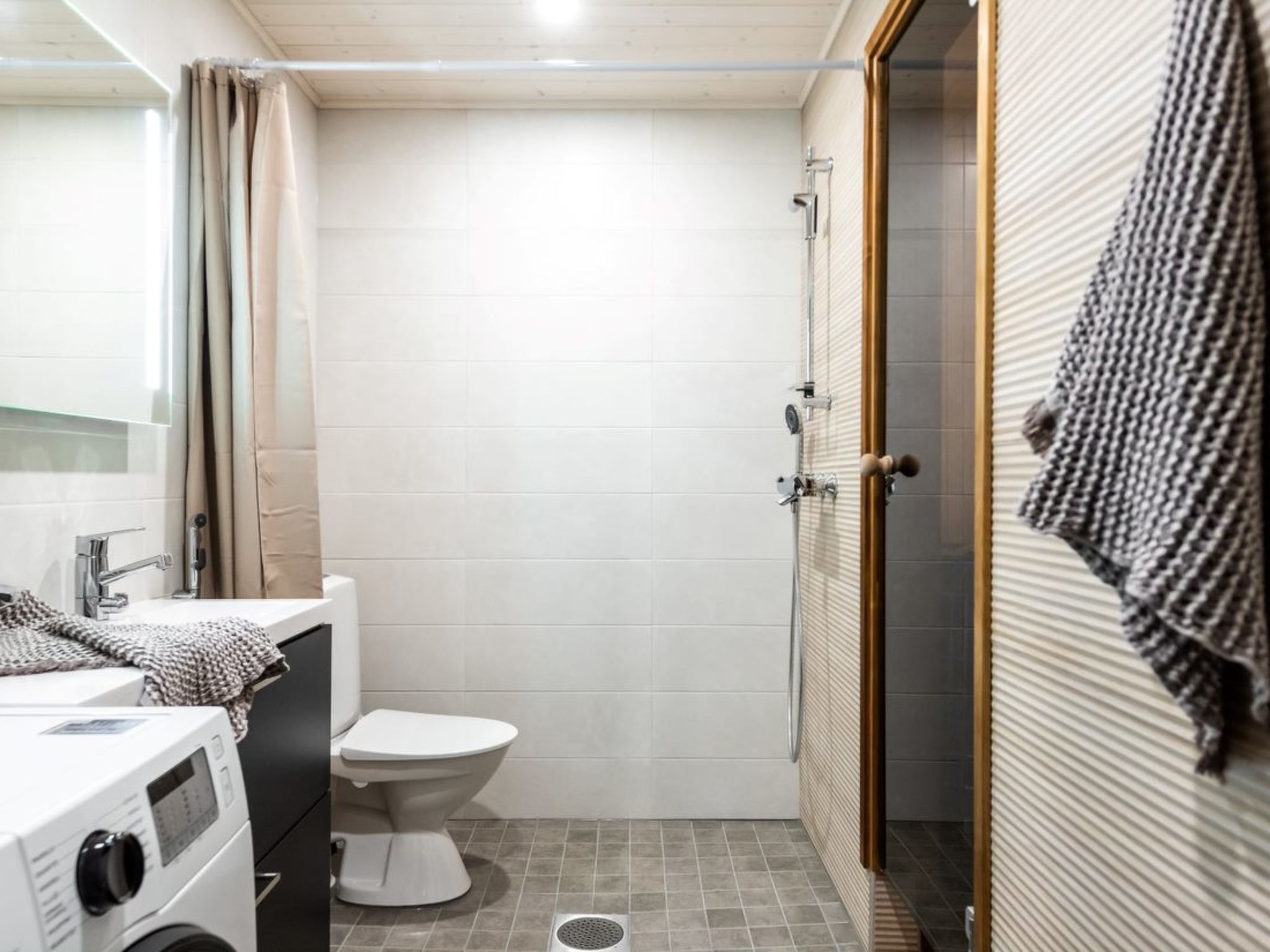 Un baño pequeño con inodoro, lavadora y zona de ducha.