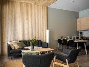 A modern living space with a sofa, a coffee table, and a dining area with chairs and a table.