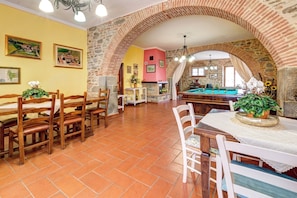 A dining area with a pool table, wooden chairs, and a brick archway. - Luxury Villa In Cortona (Cortona)