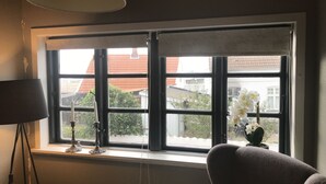 Una habitación con un ventanal grande, una lámpara y una silla.