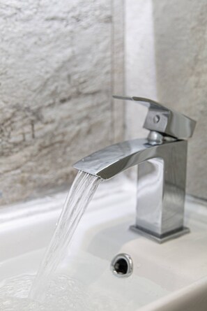 Ein modernes Waschbecken mit chromfarbenem Wasserhahn und sichtbarem Ablauf.