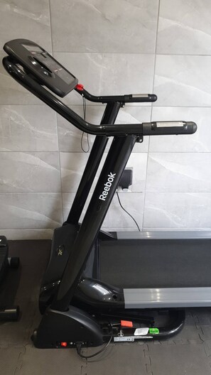Ein stehendes Ergometer mit Bedienfeld, Display und Fußpedal.