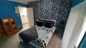 Une chambre à coucher avec un lit, une armoire et une salle de bain visible à travers une porte ouverte.