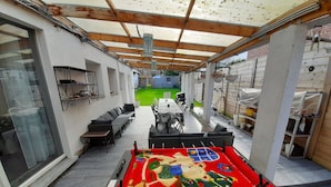 Une terrasse extérieure avec une table de billard, un espace salon et une allée couverte.