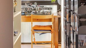 A room with a wooden desk, a chair, and a bookshelf filled with books.