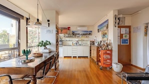 A modern kitchen with a wooden dining table, chairs, and a hanging light fixture.