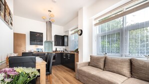 Una cocina moderna con armarios negros, una mesa de comedor de madera y un sofá junto a un amplio ventanal.