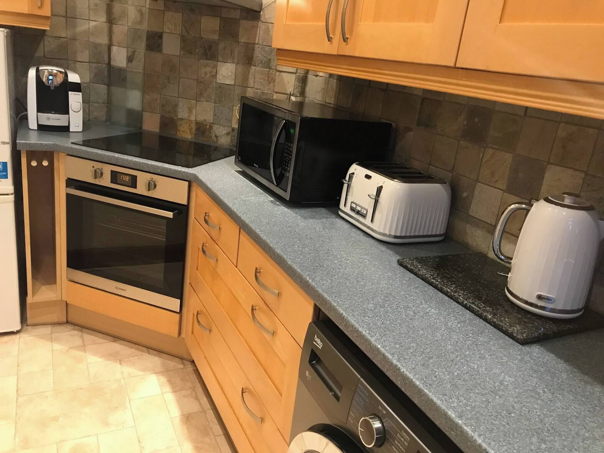 Een keuken met een magnetron, broodrooster, waterkoker, oven en vaatwasser.