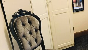 A chair with a tufted backrest and a cushioned seat, positioned in front of a white door with a glass panel. - Station View Lodge - Near Balbirnie House Markinch (Glenrothes)