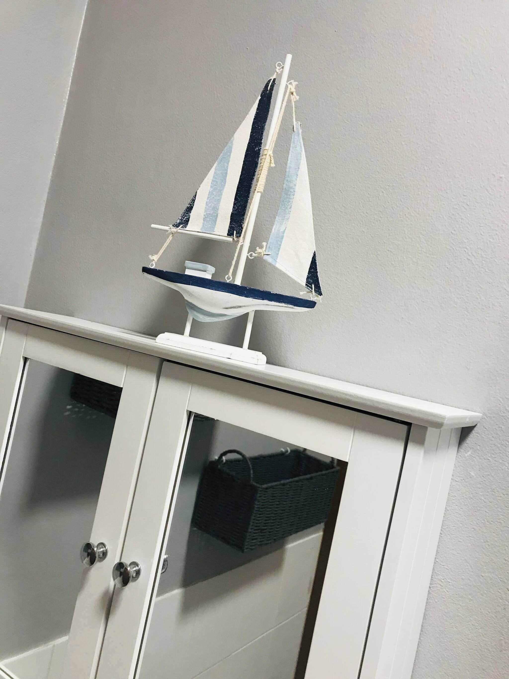 Un mueble blanco con un modelo de velero en la parte superior.