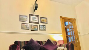 A room with a striped sofa, a wooden door, and framed pictures on the wall. - Station View Lodge - Near Balbirnie House Markinch (Glenrothes)