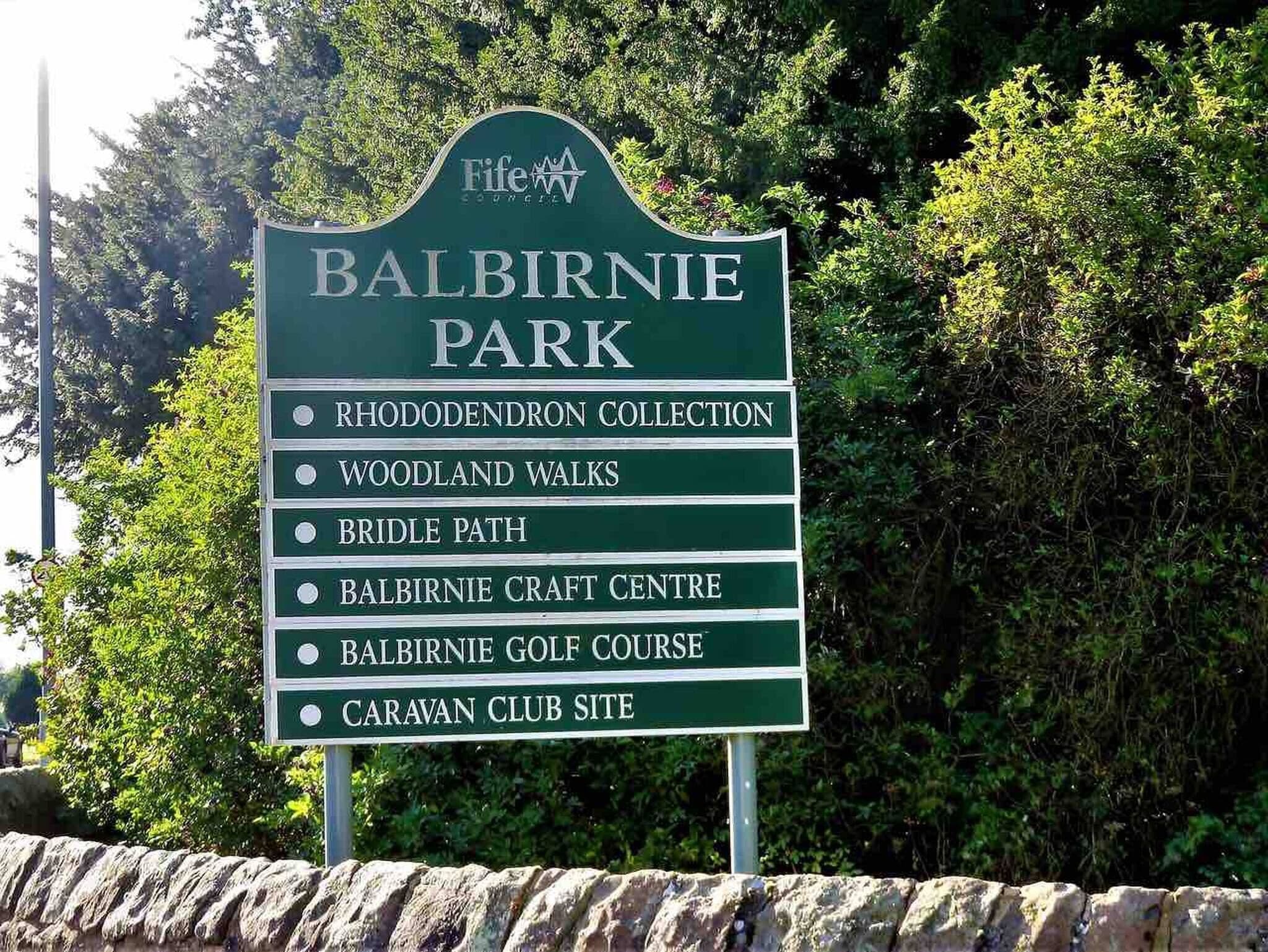 Ein Schild mit Sehenswürdigkeiten in Balbirnie Park, darunter die Rhododendronsammlung, Waldspaziergänge, ein Reitweg, das Balbirnie Handwerkszentrum, der Balbirnie Golfplatz und der Caravan Club Stellplatz.