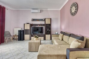 Ein Wohnzimmer mit Sofa, Couchtisch, Fernseher und Regalen.