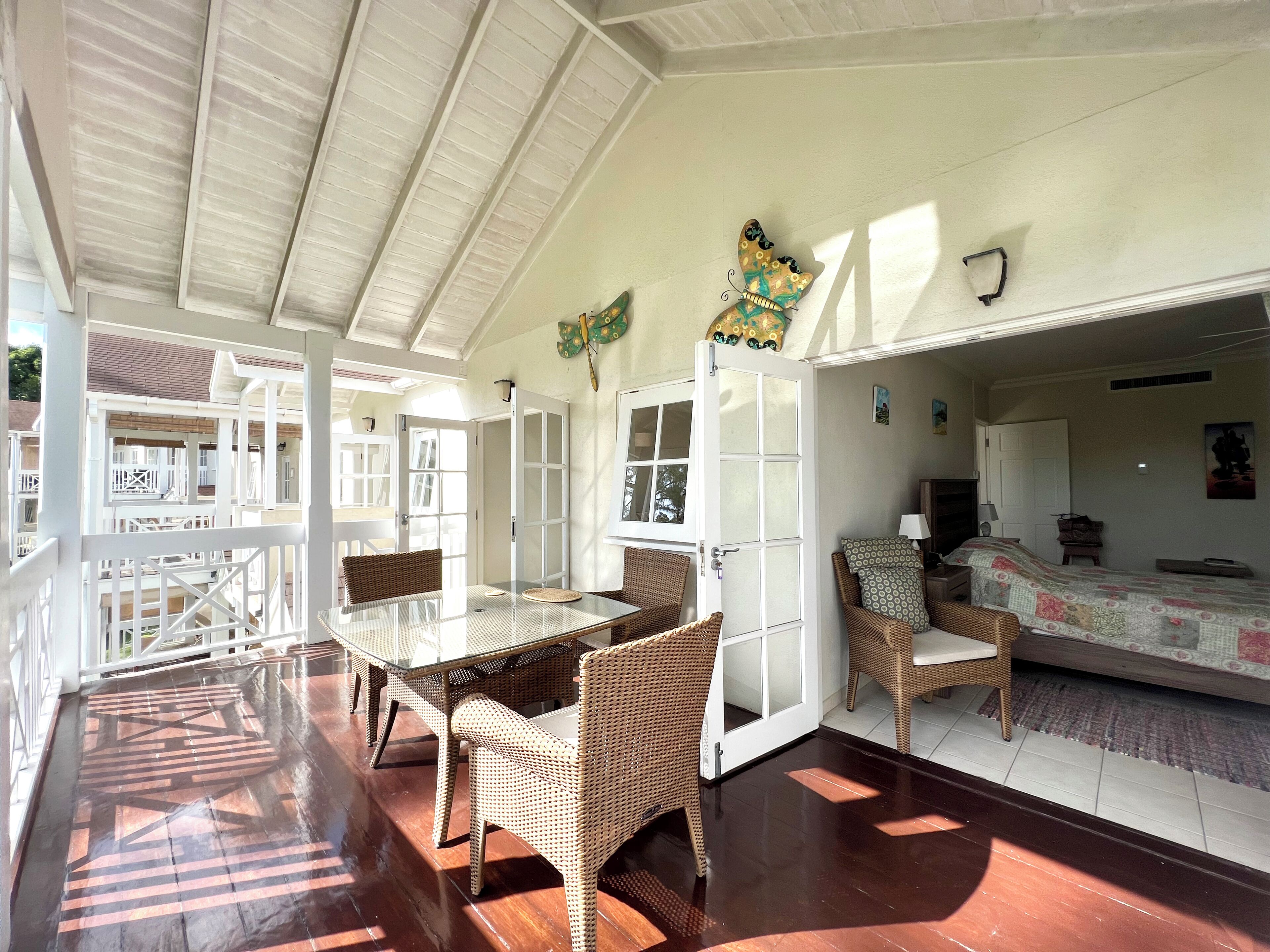 Una habitación amplia con una gran mesa de comedor, sillas de mimbre y una zona de cama acogedora.