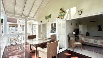 Una habitación amplia con una gran mesa de comedor, sillas de mimbre y una zona de cama acogedora.