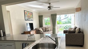 Una cocina moderna con un lavamanos integrado, una zona de comedor con un sofá y un balcón con cortinas.