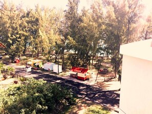 Un espace de stationnement avec plusieurs tentes et une structure rouge, le tout entouré d’arbres.