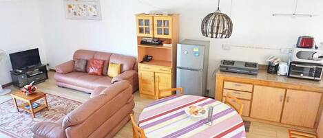 Um espaço compacto para relaxar, com sofá, mesa de jantar, cozinha compacta e televisão.